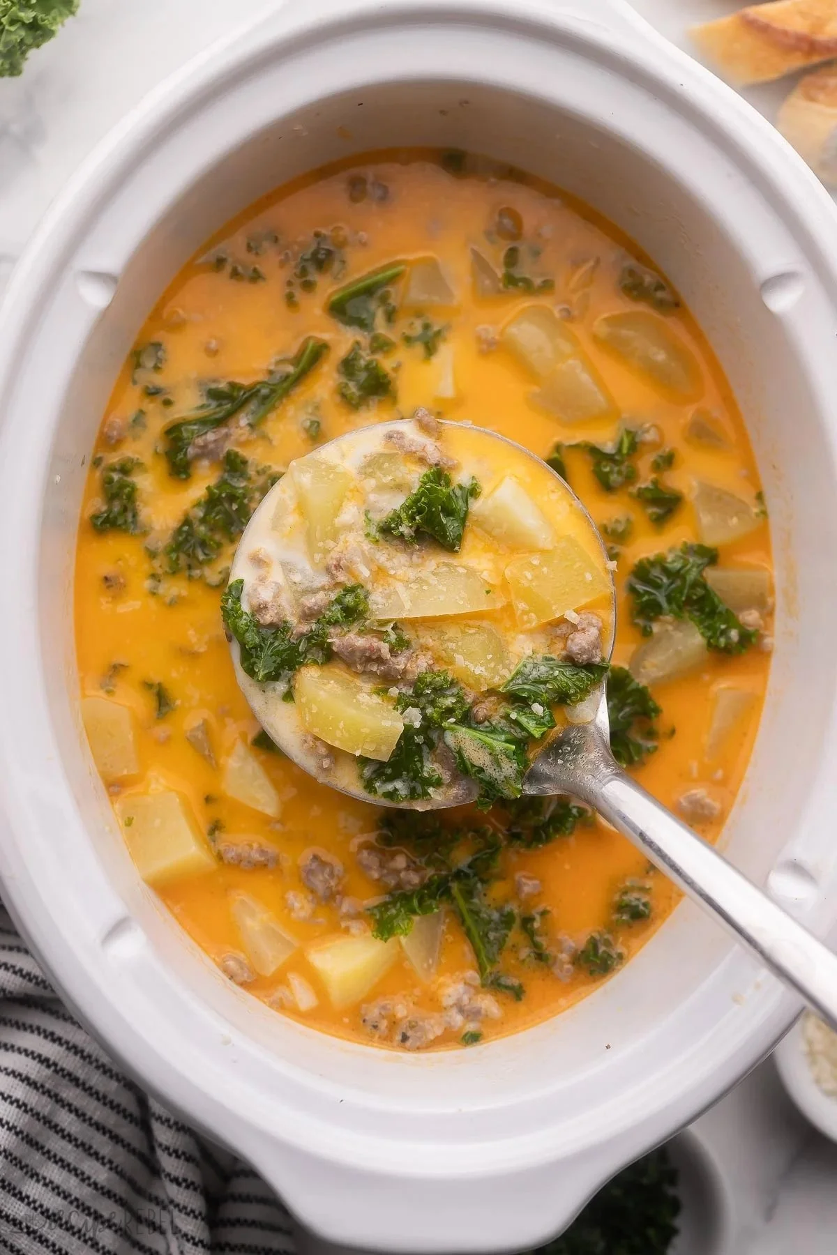 Bowl of Crockpot Tuscan Soup with fresh ingredients and herbs
