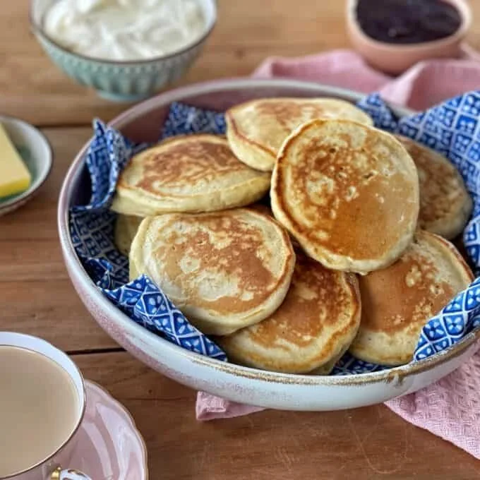 A stack of fluffy pikelets topped with fresh berries and syrup