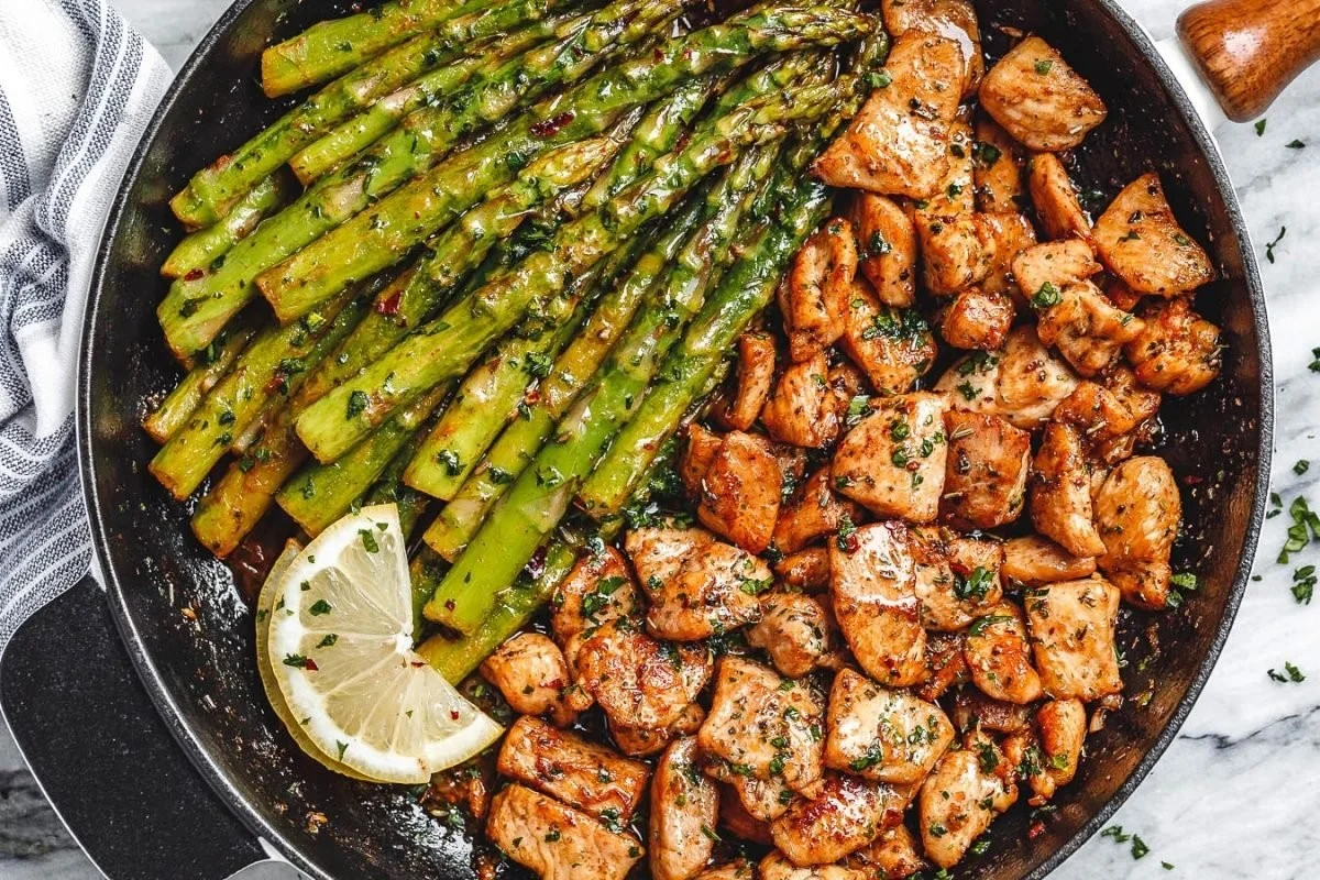 Delicious garlic butter chicken bites served with fresh asparagus