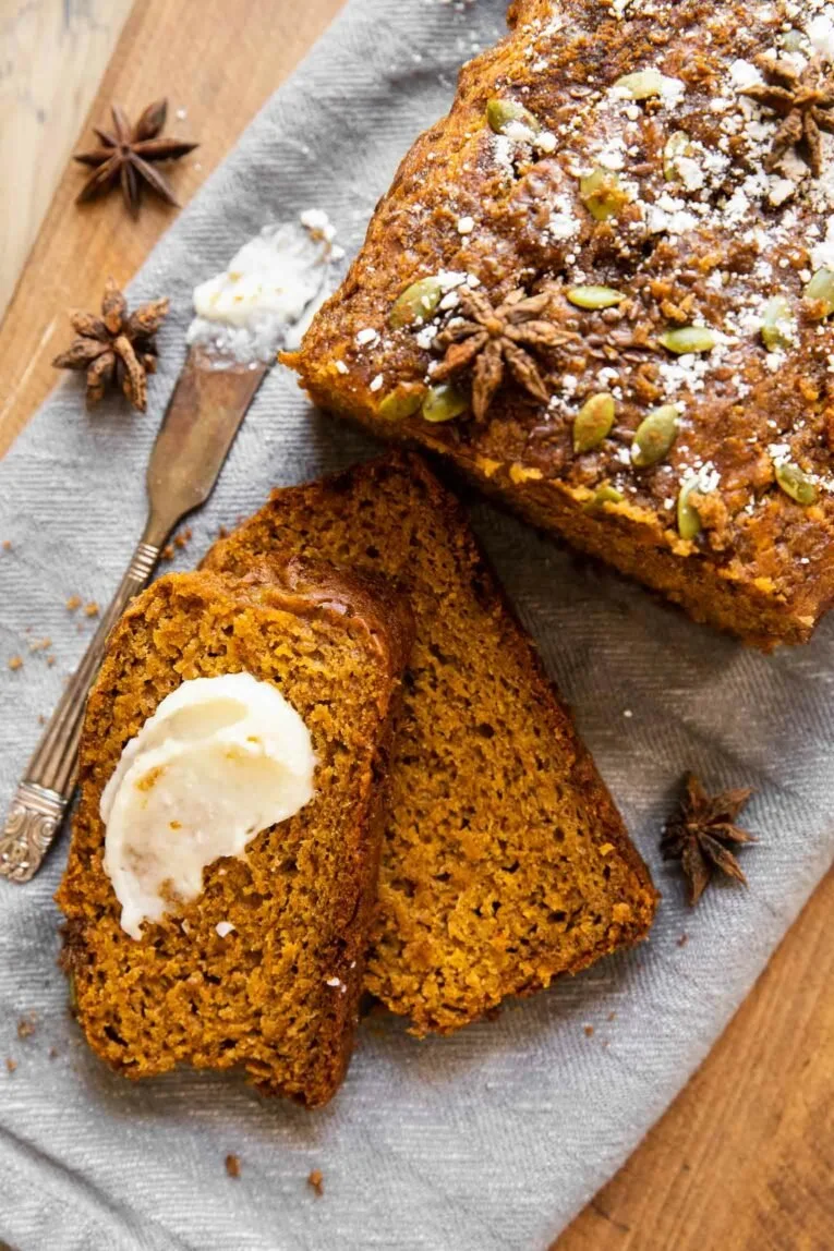 Loaf of healthy pumpkin bread with spices and walnuts on a wooden table.
