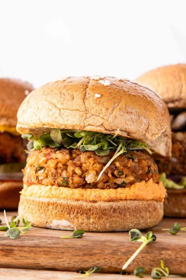 Hearty homemade veggie burgers served on a wooden platter with fresh toppings.