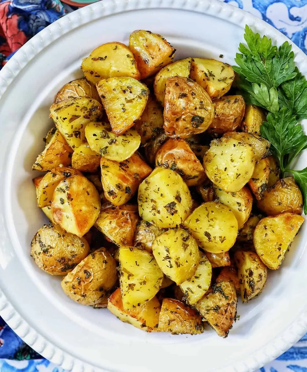 Bowl of Herby Potatoes garnished with fresh herbs and spices