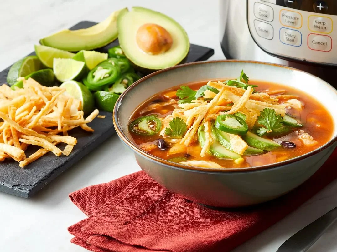 Bowl of Instant Pot Chicken Tortilla Soup topped with avocado and cilantro