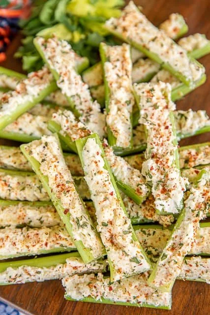Italian cream cheese stuffed celery on a white plate garnished with herbs