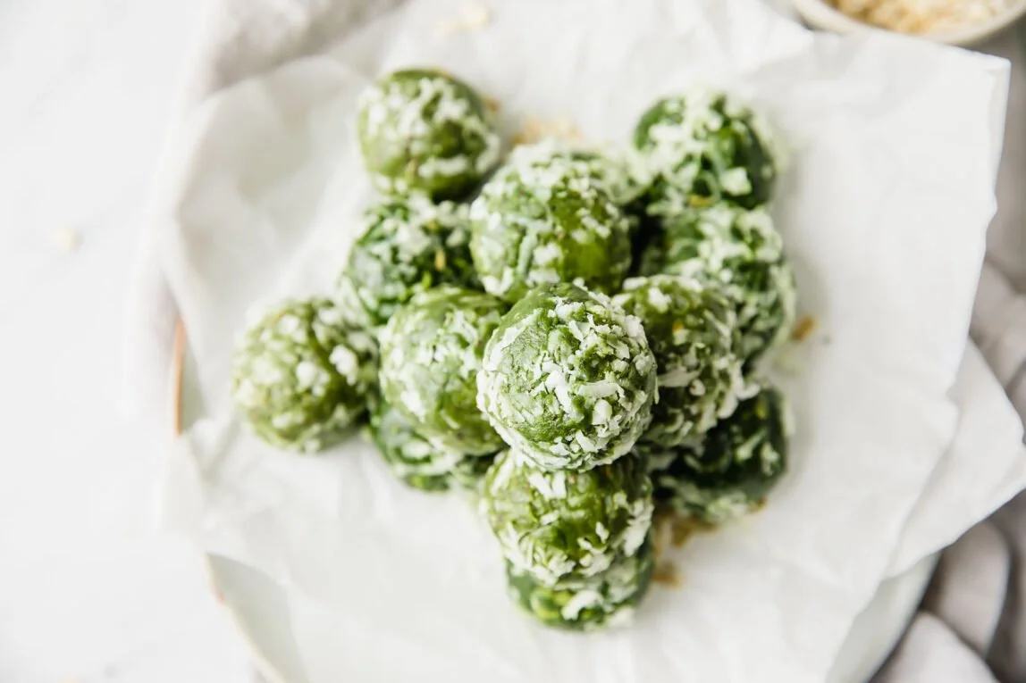 Matcha Chia Seed Energy Bites in a bowl with green tea leaves in the background.