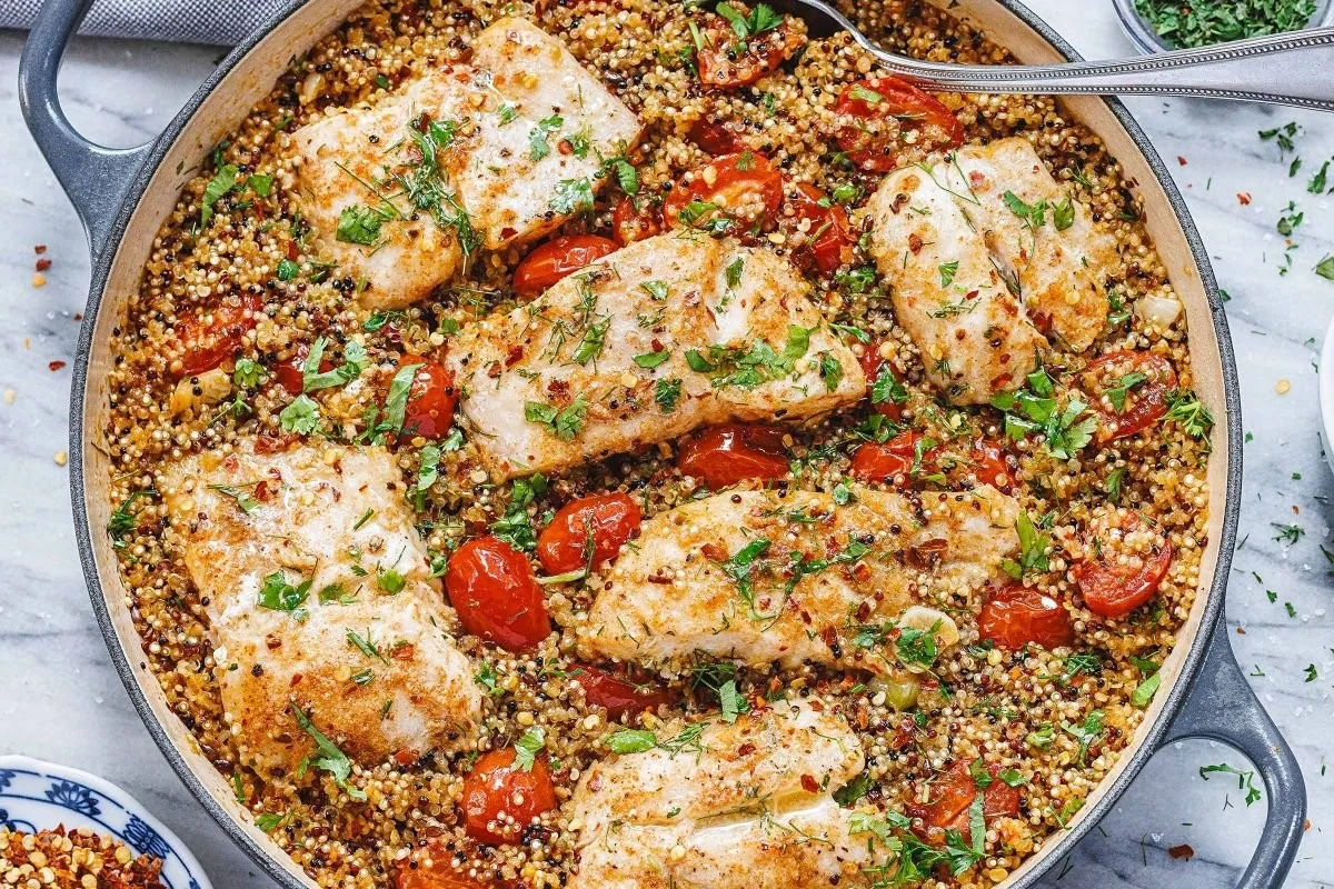 One-pan fish fillets with quinoa served on a plate, garnished with herbs.