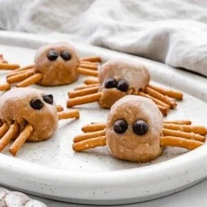 Plate of peanut butter spiders dessert decorated with pretzels and chocolate.