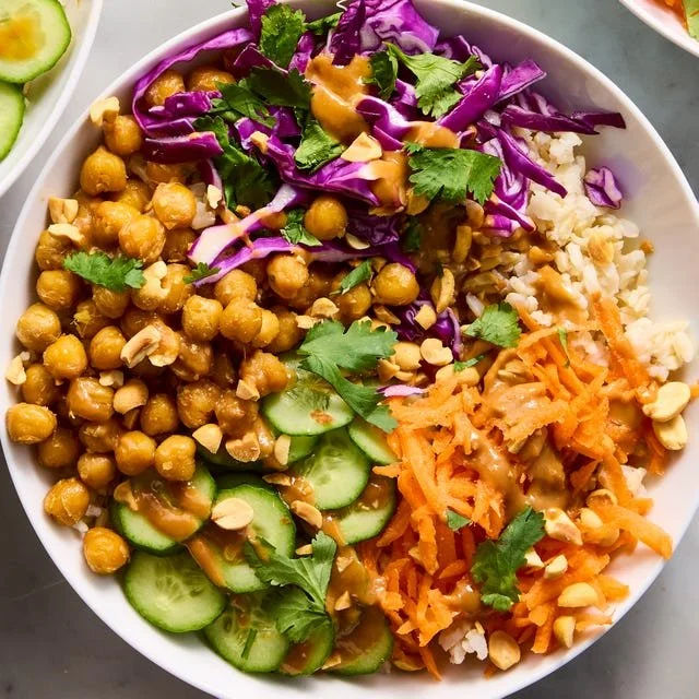 Healthy Peanut Chickpea Protein Bowls topped with fresh vegetables and sauce