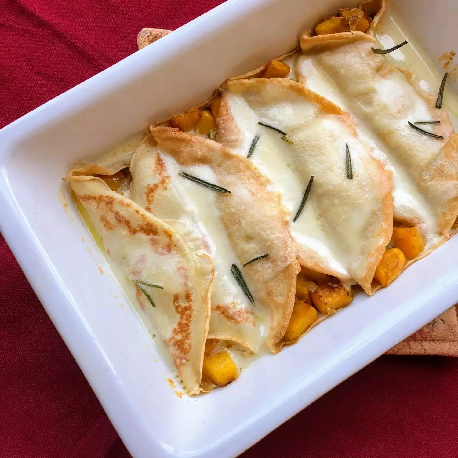 Pumpkin crepes with fontina cheese sauce served on a plate