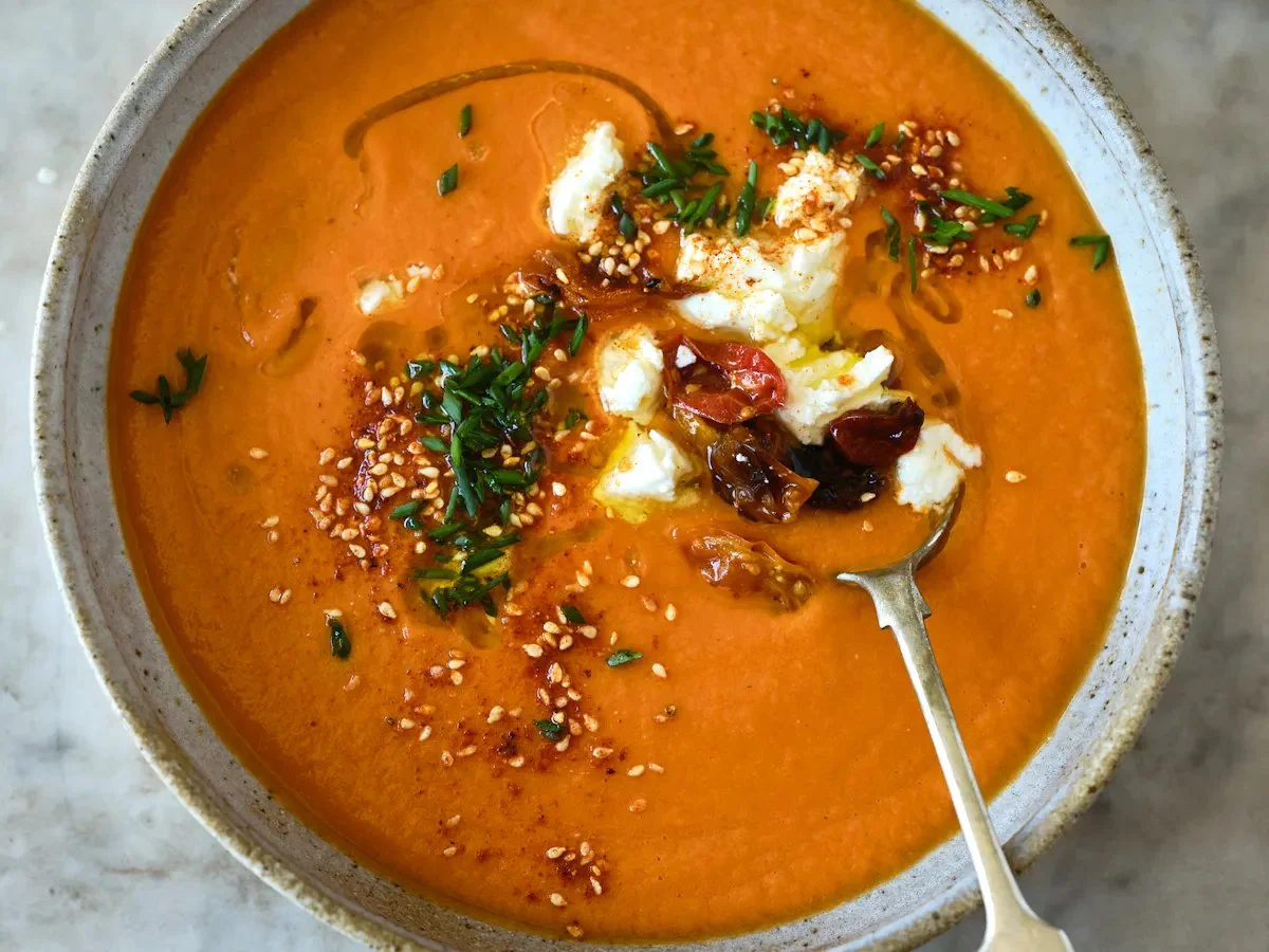 Delicious bowl of roasted tomato soup garnished with fresh herbs and served hot.