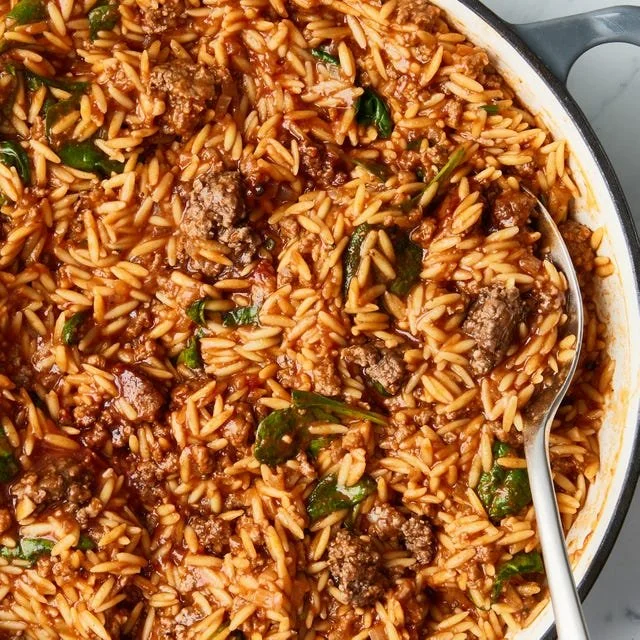 Bowl of Sloppy Joe Orzo topped with herbs and served with a spoon.