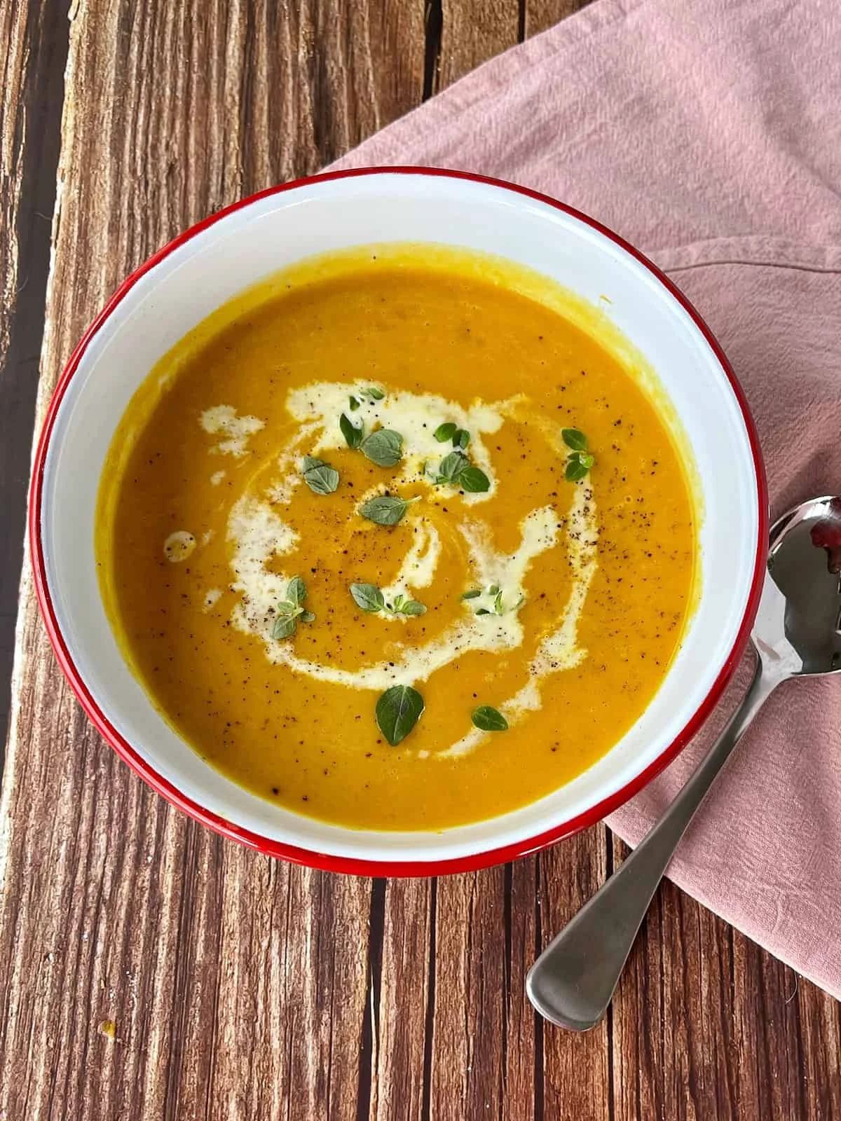 Bowl of delicious slow cooker pumpkin soup garnished with herbs.
