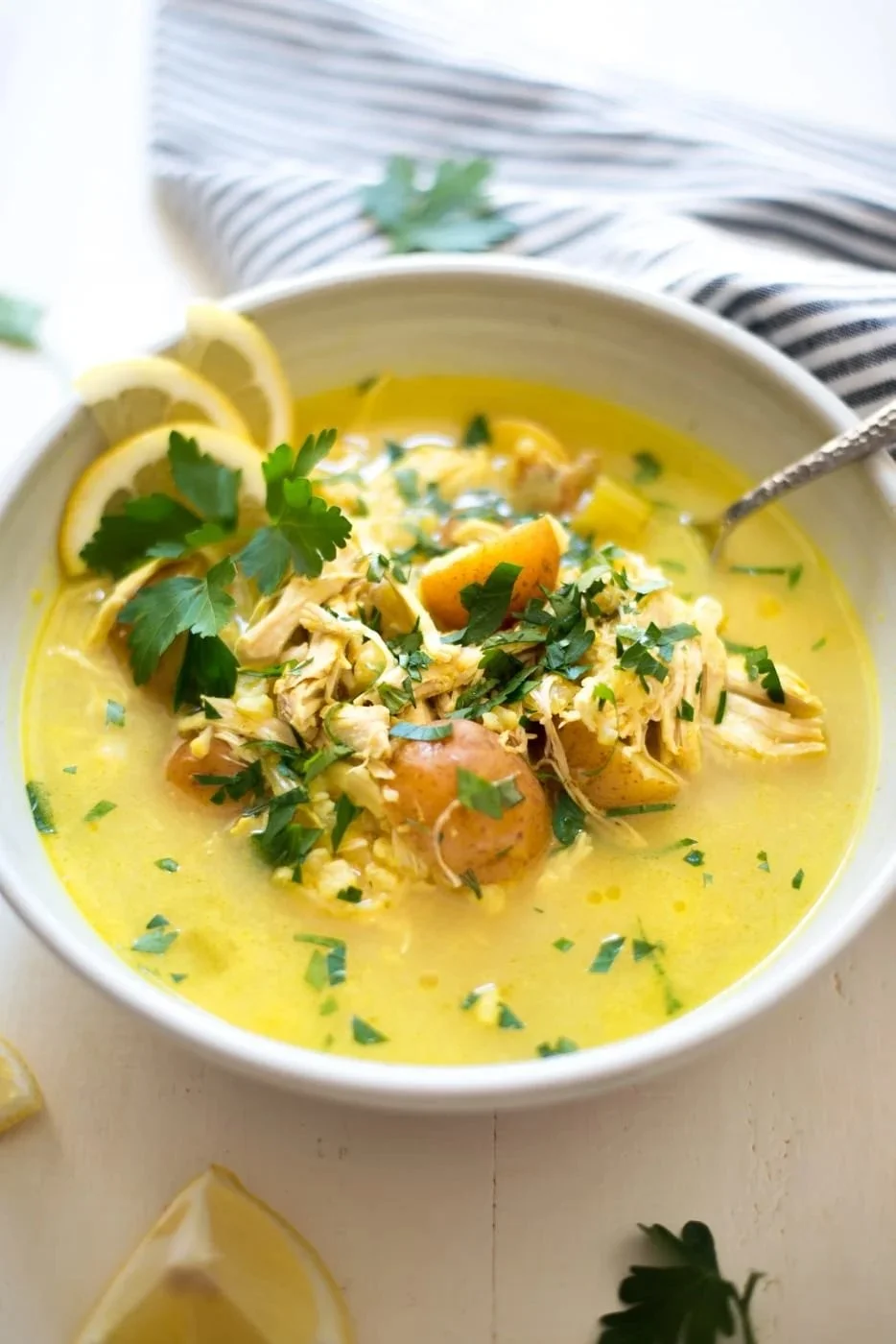 A bowl of Slow Cooker Sunshine Lemon Chicken Chowder with fresh herbs and lemon slices