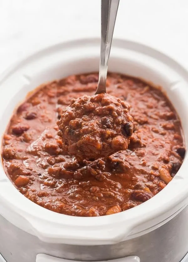 Bowl of delicious Slow Cooker Three Bean Beef Chili topped with fresh herbs