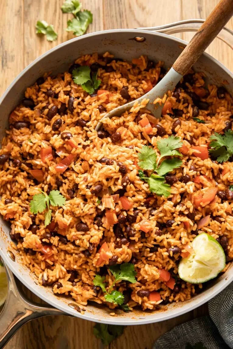 A plate of Spanish rice and beans garnished with fresh herbs