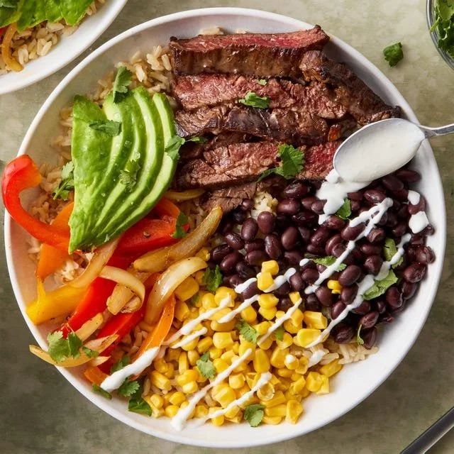 Healthy steak fajita power bowls with fresh vegetables and spices
