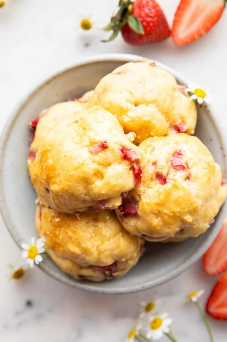 Strawberry drop pancake bites served on a plate with fresh strawberries