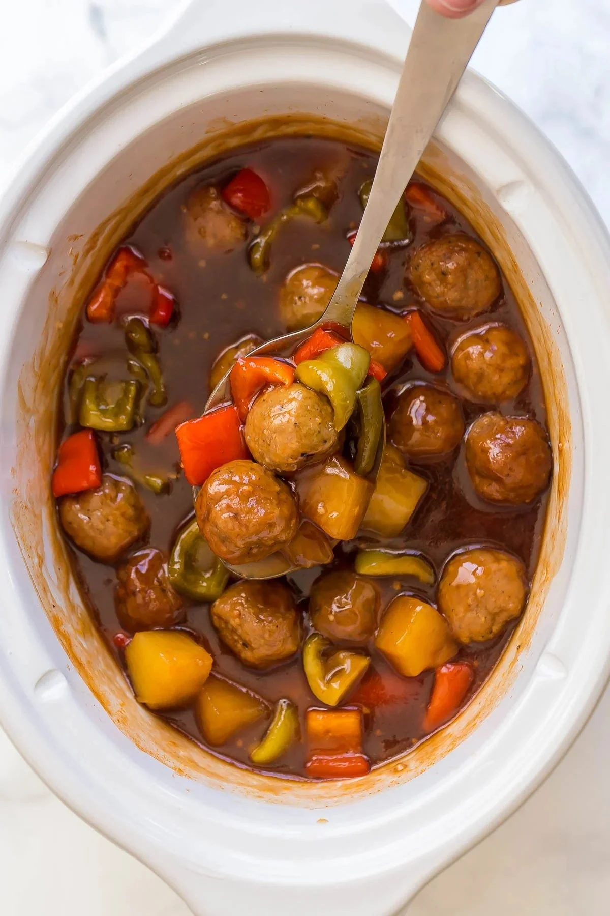 Sweet and Sour Crockpot Meatballs served in a bowl with sauce and garnish.