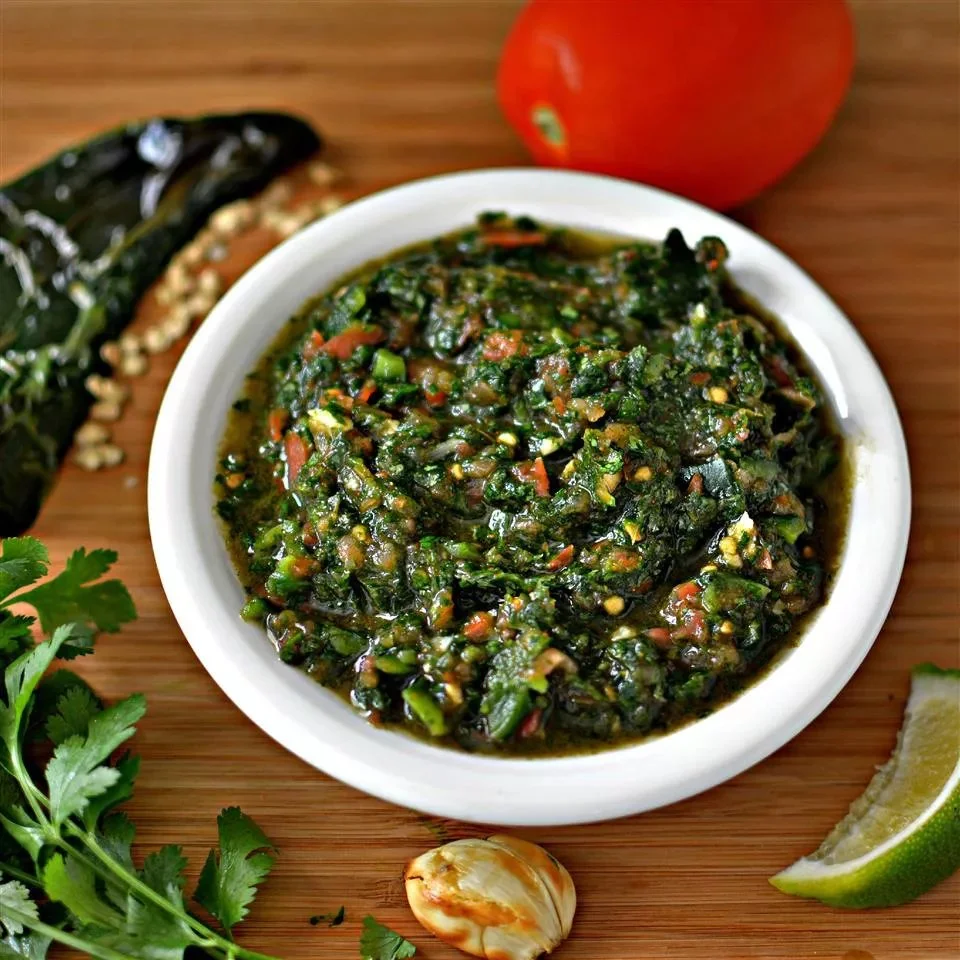 Tomato salsa without onions served in a bowl with fresh herbs and lime.