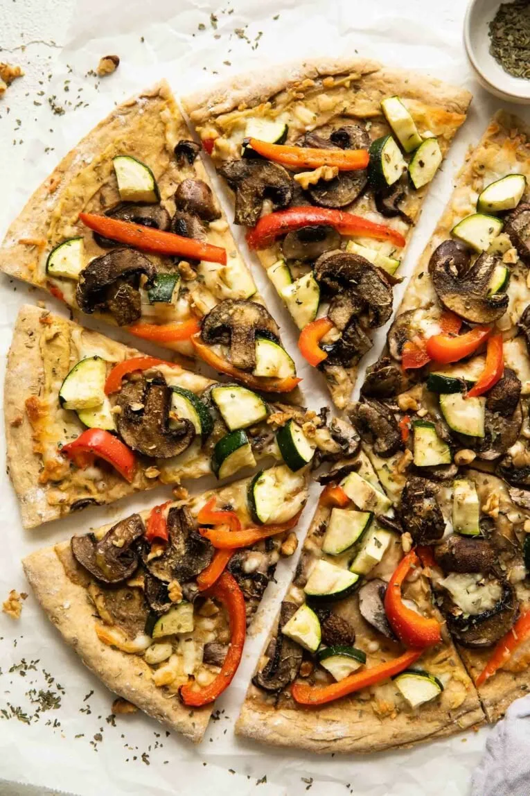 Vegan Red Pepper Hummus Pizza with fresh toppings on a wooden platter