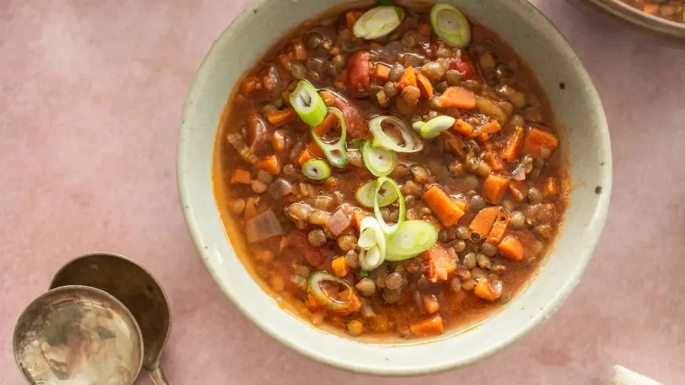 Bowl of hearty Lentil-Veggie Soup with fresh vegetables and herbs