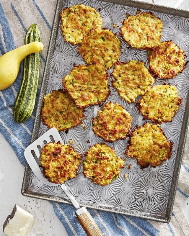 Zucchini-and-Pecorino fritters served on a plate, garnished with herbs.