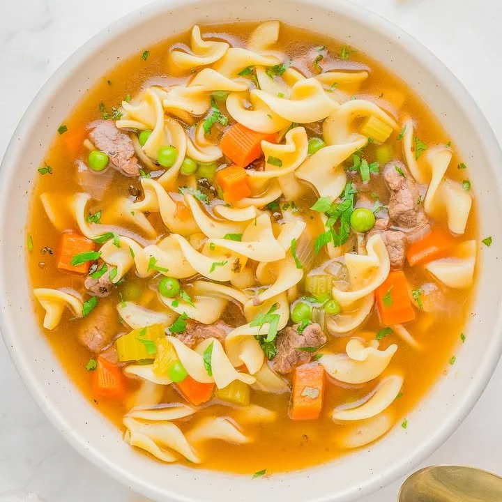 A delicious bowl of beef noodle soup with fresh herbs and noodles