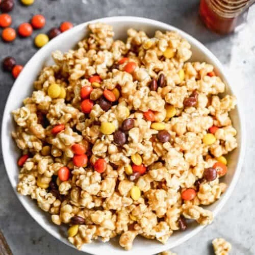 Bowl of peanut butter popcorn drizzled with chocolate and sprinkled with peanuts.