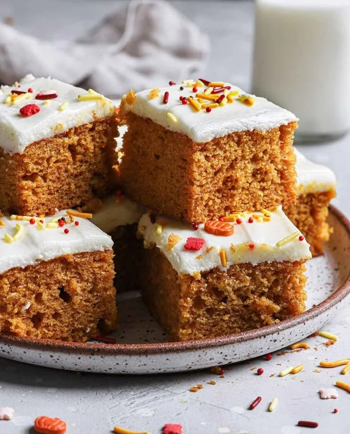 Delicious pumpkin bars topped with creamy cream cheese frosting on a rustic wooden table