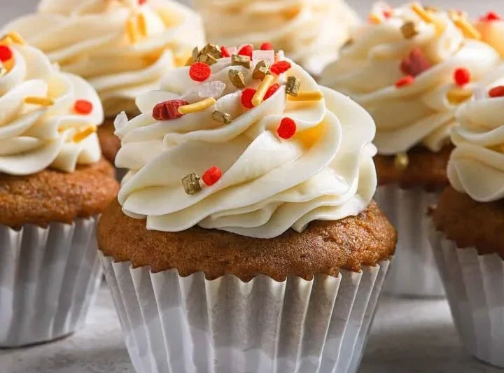 Pumpkin cupcakes topped with cream cheese frosting on a decorative plate