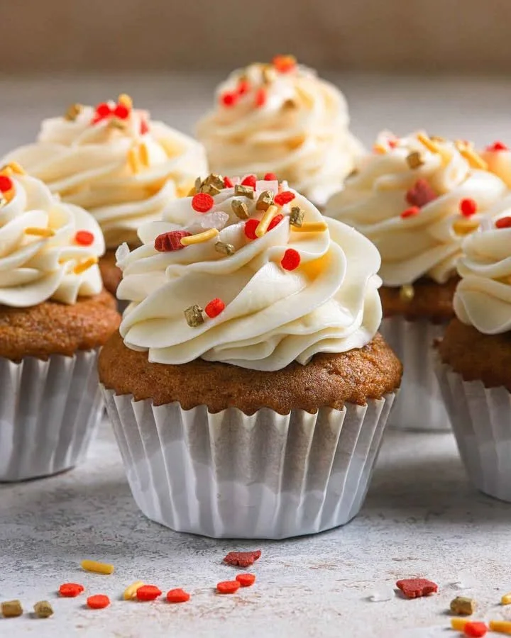 Pumpkin cupcakes topped with cream cheese frosting on a decorative plate