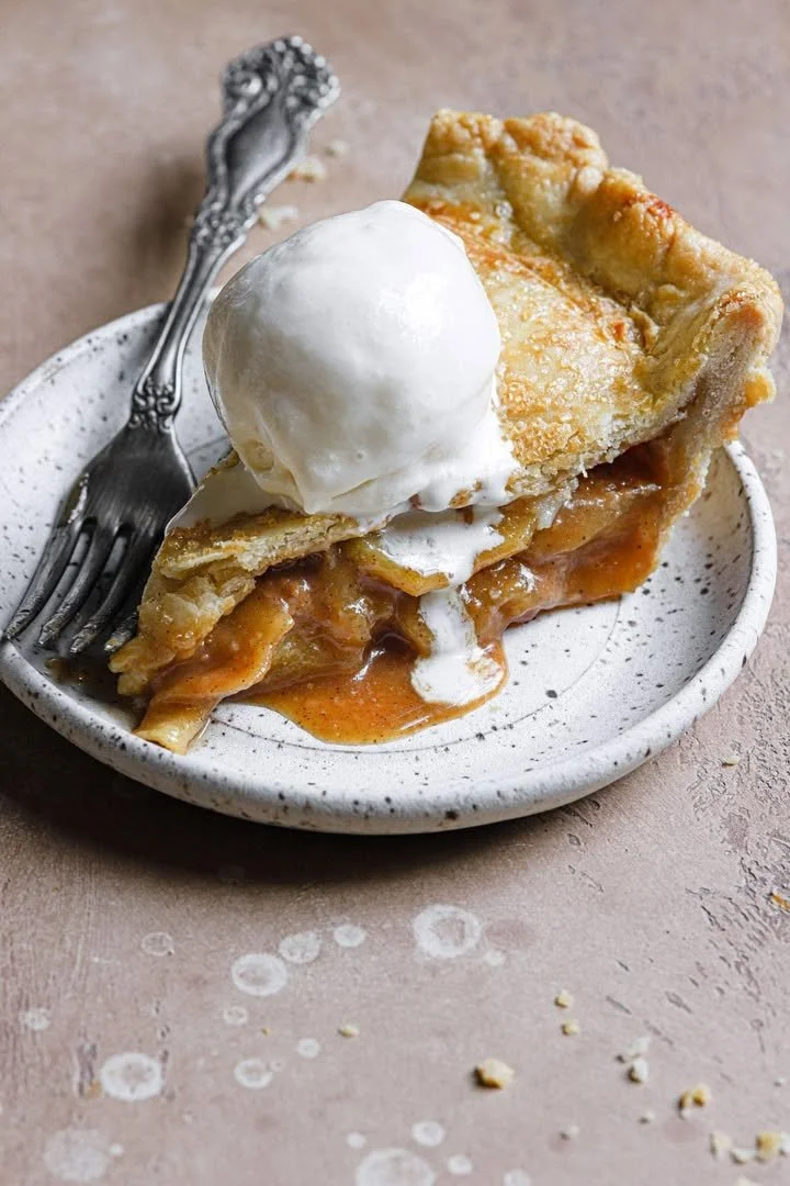 Slice of salted caramel apple pie with a golden crust and drizzled caramel