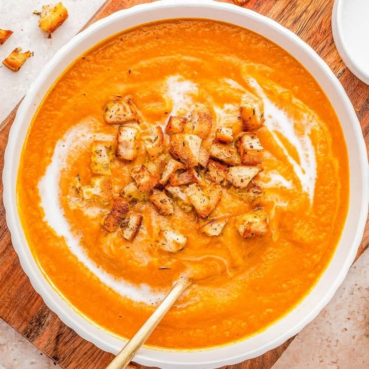 Bowl of slow cooker pumpkin soup topped with spices and herbs