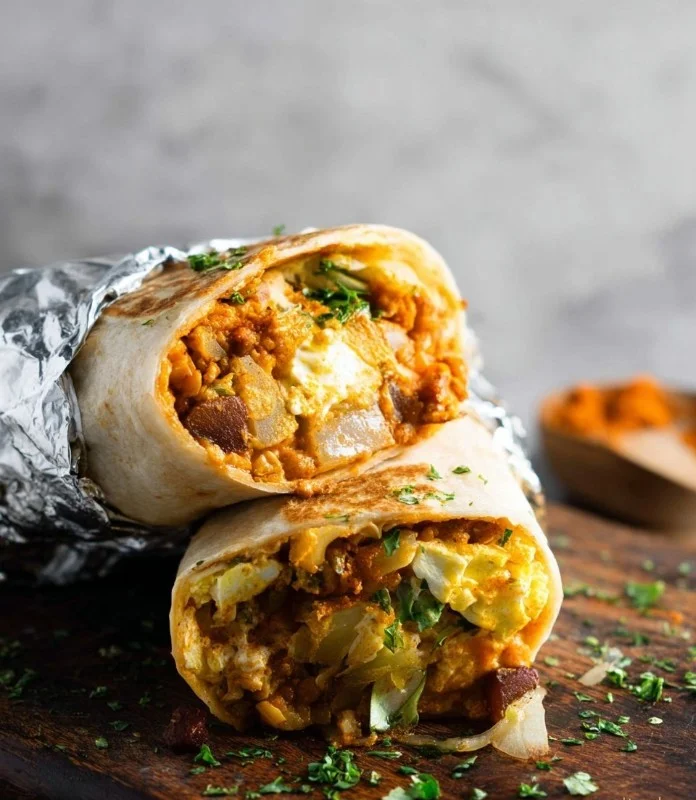 Plate of delicious vegan breakfast burritos with fresh vegetables and spices.