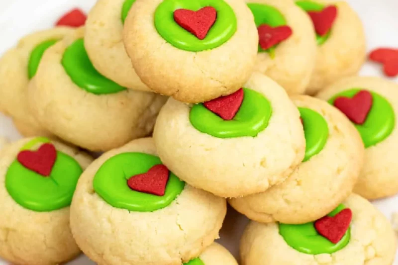 Festively decorated Grinch style thumbprint cookies with green and red designs.