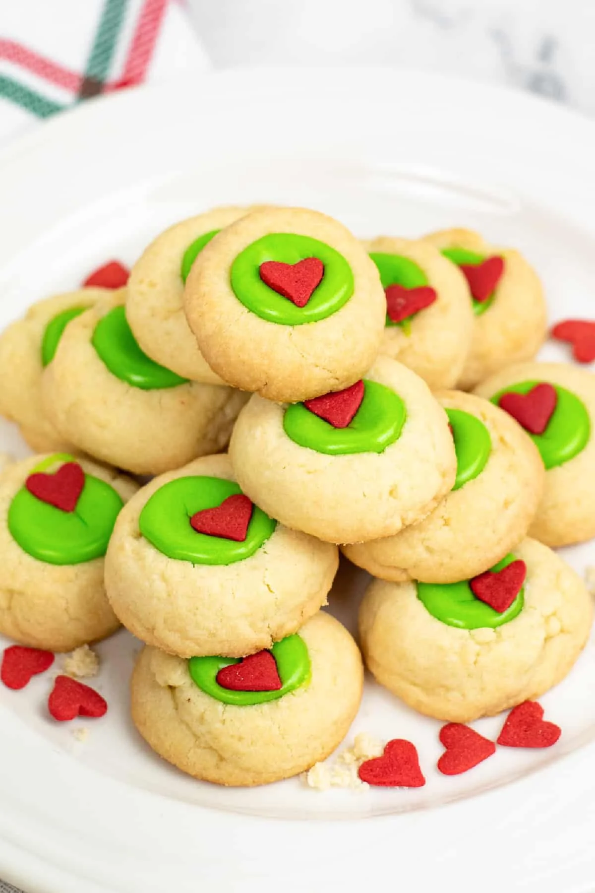 Festively decorated Grinch style thumbprint cookies with green and red designs.
