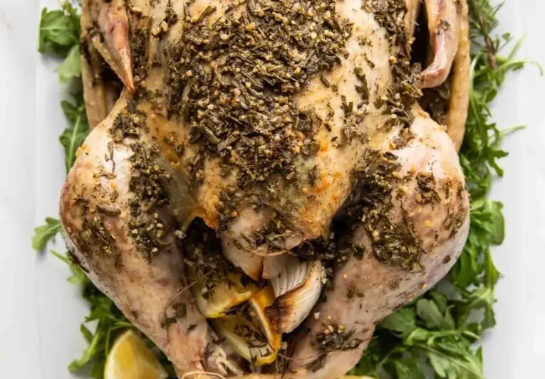 Juicy Herb Butter Roasted Turkey garnished with fresh herbs on a festive table