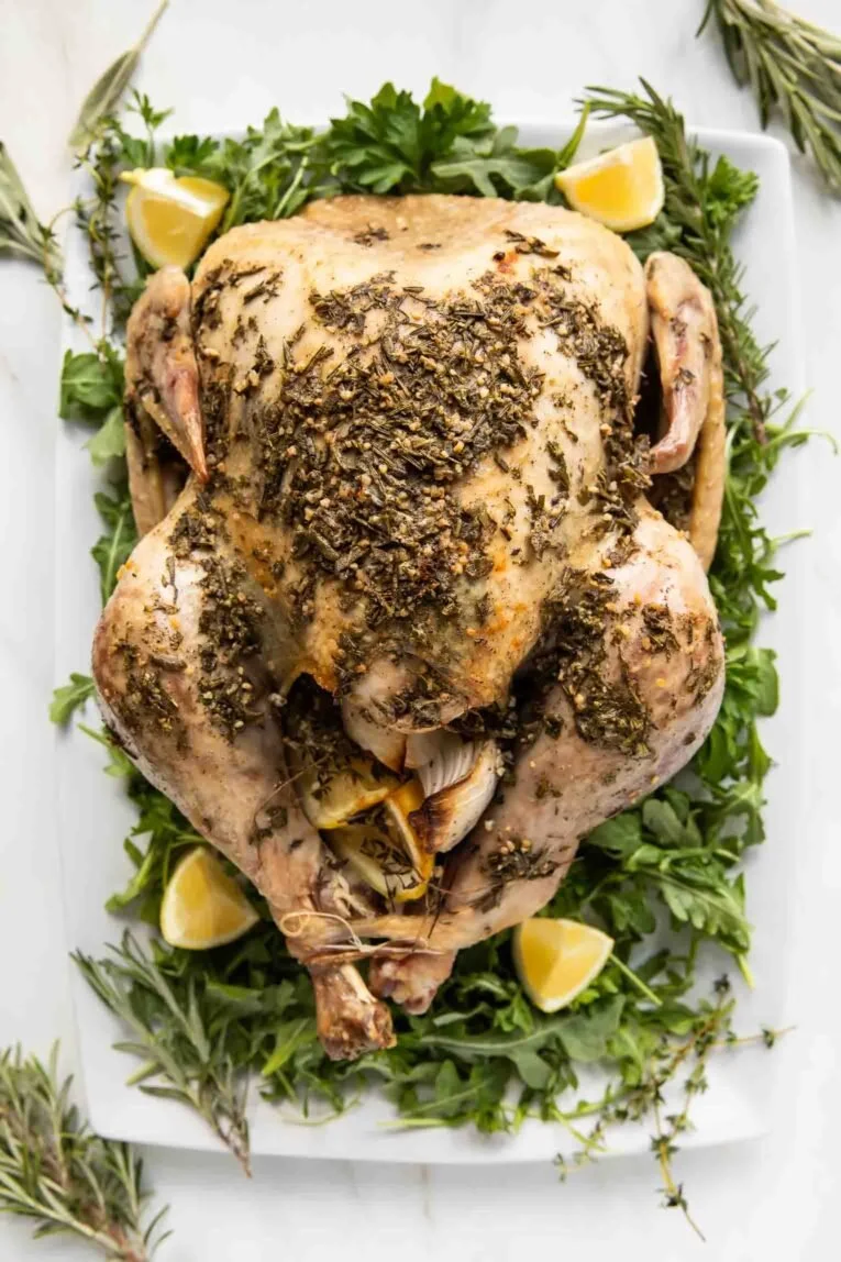 Juicy Herb Butter Roasted Turkey garnished with fresh herbs on a festive table